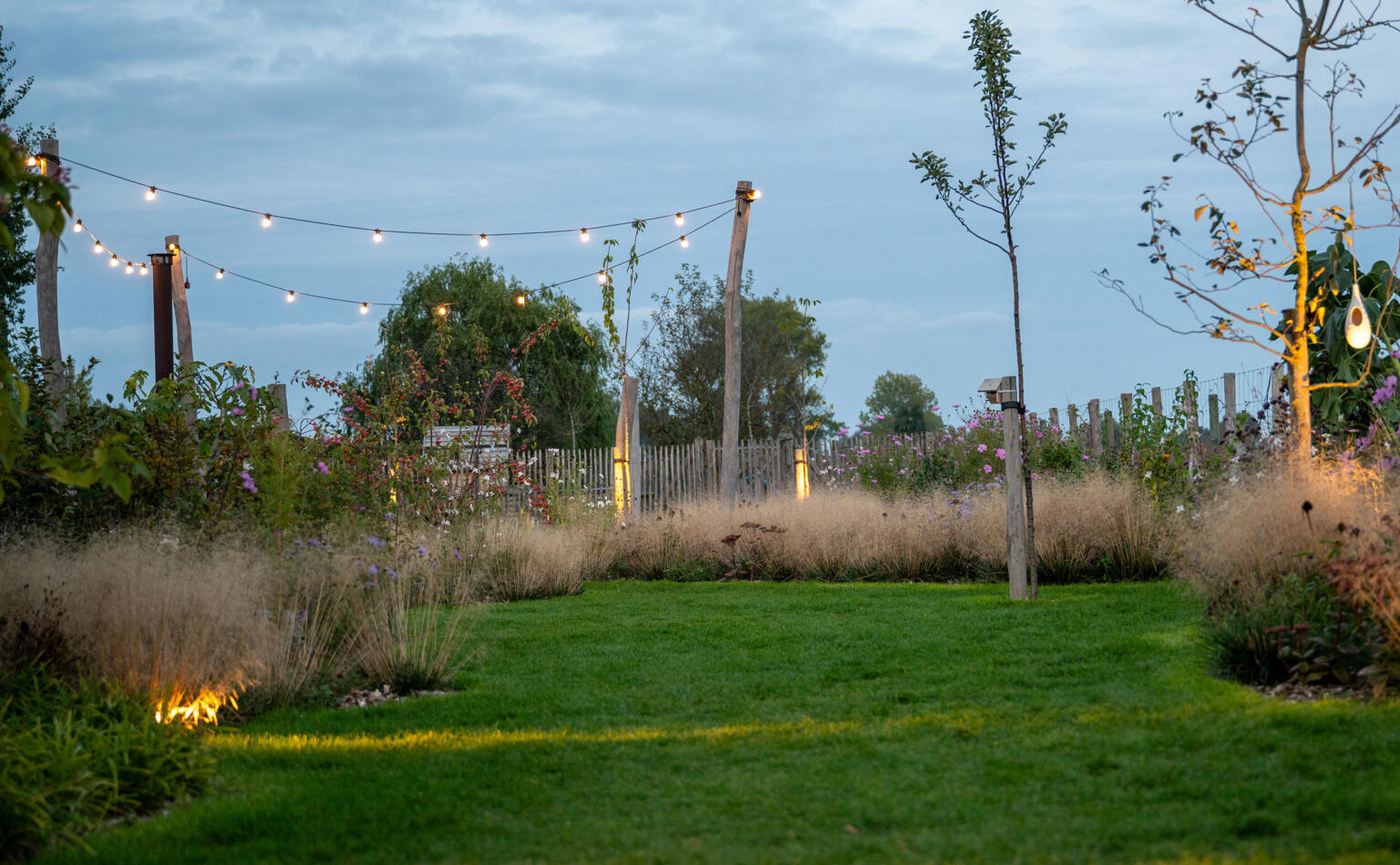 Greenarchitects stefaan willems tuinarchitectuur overschelde oost vlaanderen serskamp realisatie verlichting golden hour guirlande robinia paal