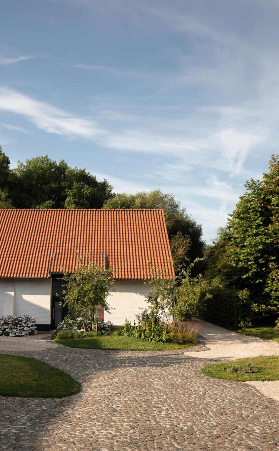 Greenarchitects stefaan willems landschapsarchitect afsnee kasseienpad met omringende groene biodiversiteit en historische gevel