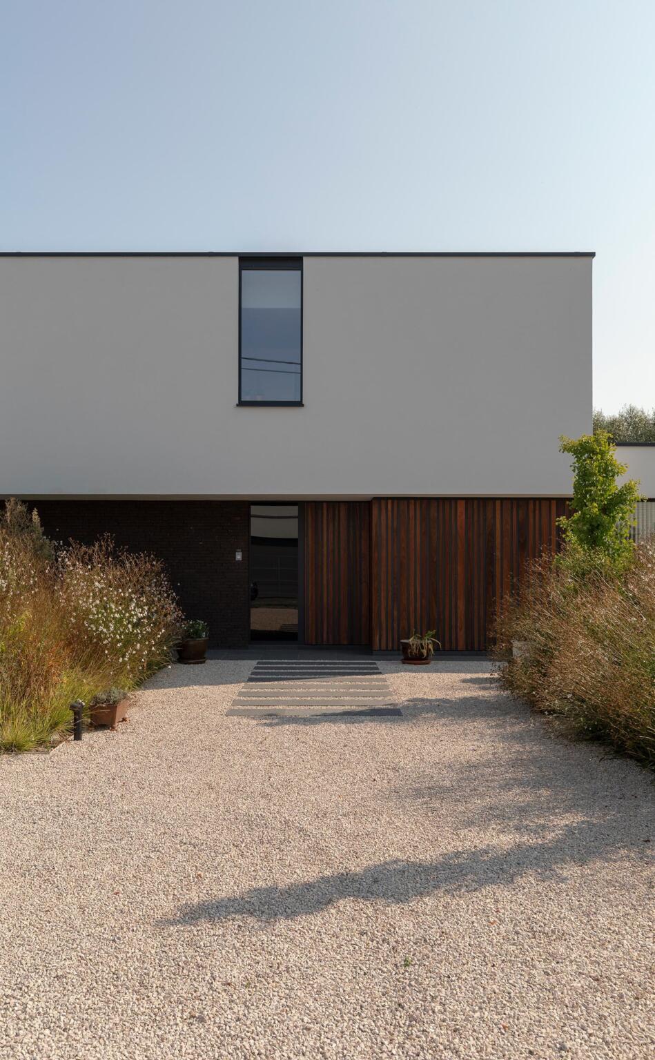 Greenarchitects stefaan willems landschapsarchitect ninove moderne woning voortuin oprit grind inkompad natuursteen taluds hoogstam ginkgo sesleria gaura soortnerijk 01